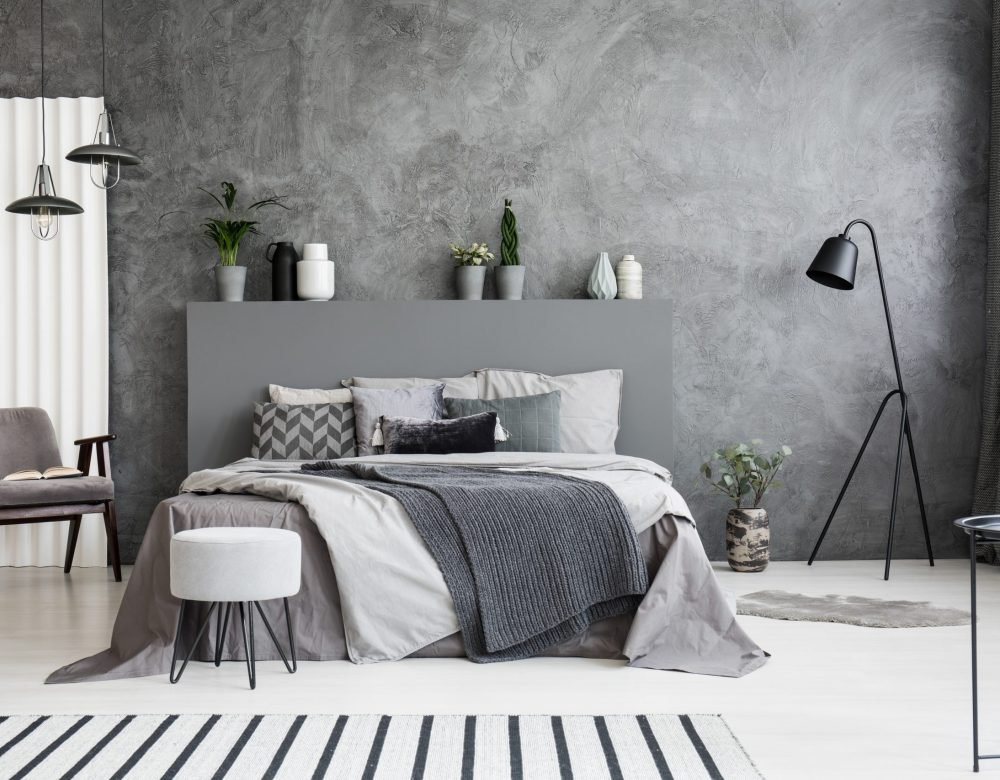 grey-armchair-and-stool-near-bed-with-headboard-in-JGXBRKQ-scaled.jpg